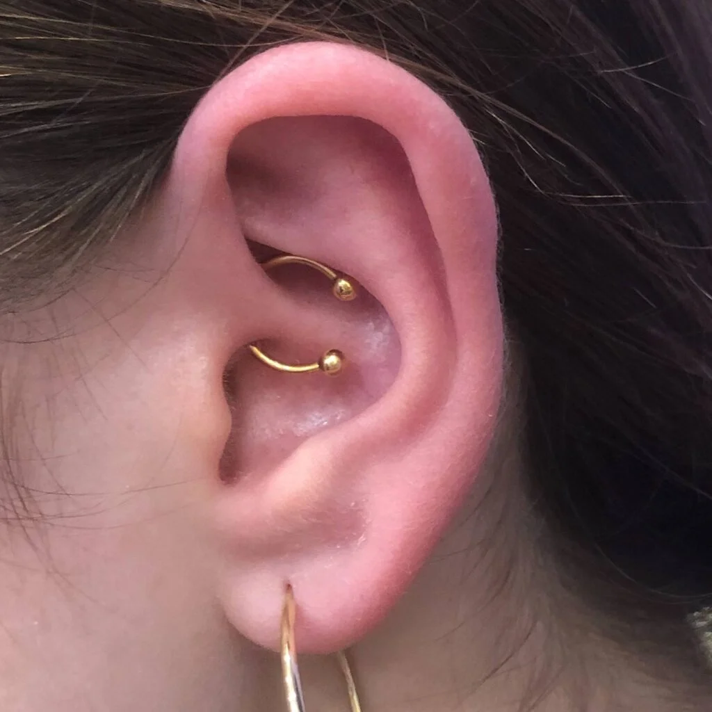 Arany színű anodizált daith piercing patkó ékszerrel Arany színű daith piercing patkó ékszerrel női fülben, alsó karika fülbevalóval