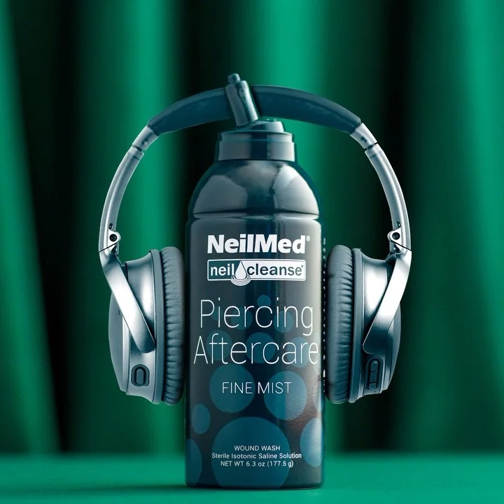 NeilMed Piercing Aftercare Spray fejhallgatóval, zöld háttéren