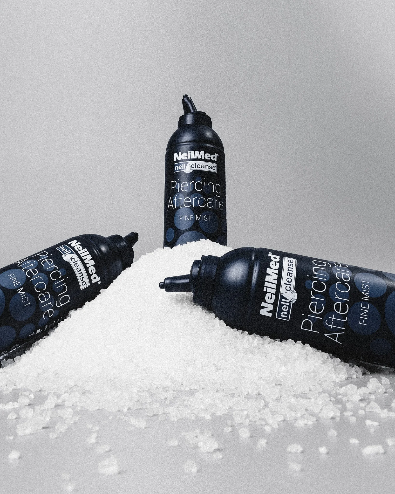 NeilMed Piercing Aftercare Spray termékek fehér sókristályokon elrendezve